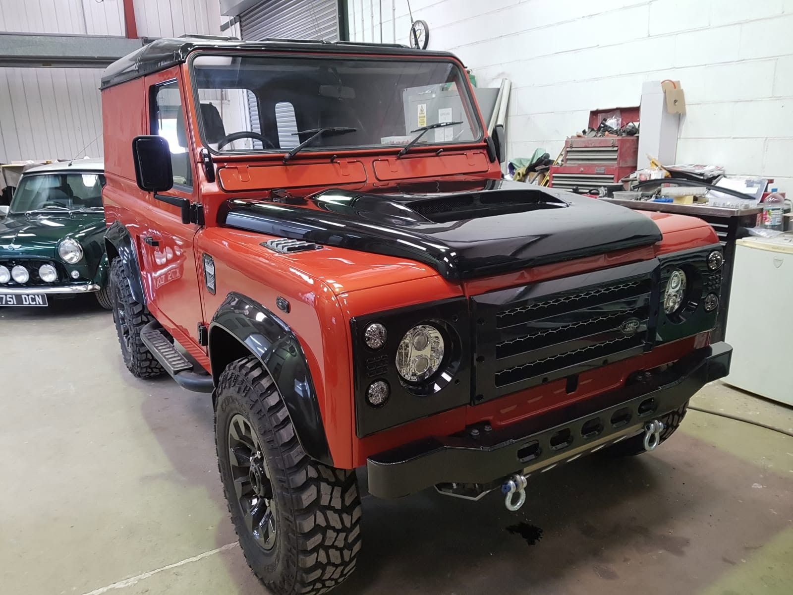 Freshly restored orange and black Land Rover Defender in the Fakenham Body Centre workshop